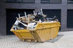 Yellow industrial skip full of disused office equipment